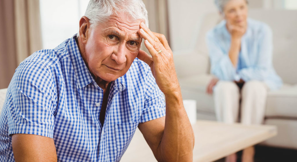 Worried Senior Man Sitting On Sofa In Living Room