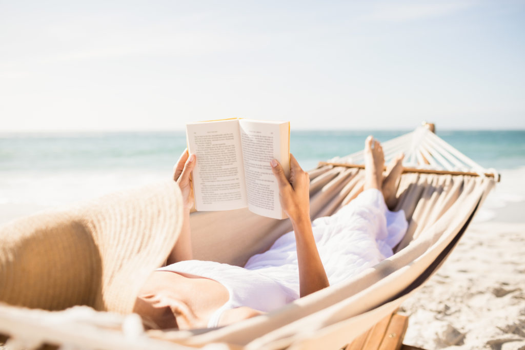 Woman reading a book on the side of the beach